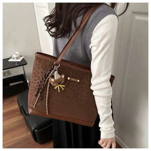 Détail du sac cabas léopard avec pendentif ours en peluche et logo en métal chic