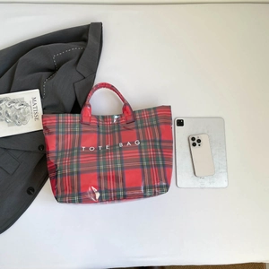 Detailed top view of a red checkered tote bag with white text on a white desk