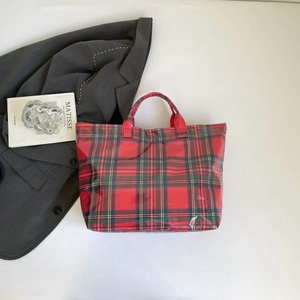 Top view of large red plaid tote bag in glossy waterproof fabric with art book background