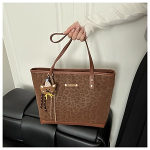 Large leopard print tote bag with brown leather handles and a cute bear pendant