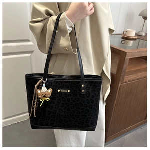 Matte leopard print tote bag with gold label and bear charm shown on a shoulder