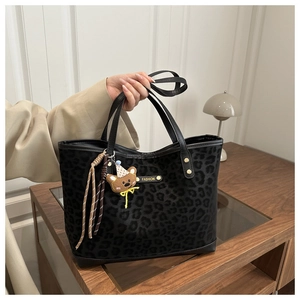 Detail of matte leopard print tote bag with plush bear charm and fashion label tag