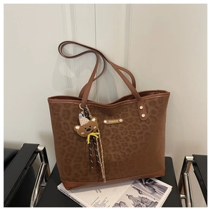 Detail of leopard print tote bag with metal FASHION logo and a cute bear charm