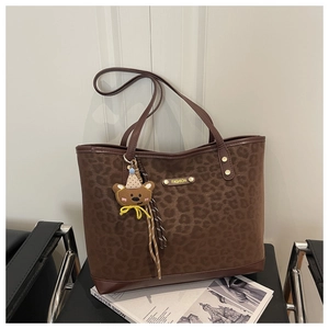 Close-up of leopard print tote bag with gold metal plate and cute teddy bear charm