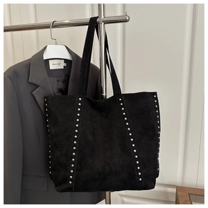 Detail of silver rivets on black suede tote bag with modern minimalist design