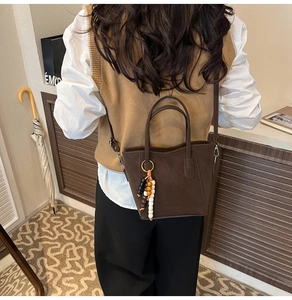 Détail du sac cabas marron foncé avec breloque perlée et fine bandoulière réglable