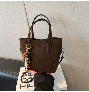 Détail d'un sac cabas marron foncé avec des perles colorées sur un livre
