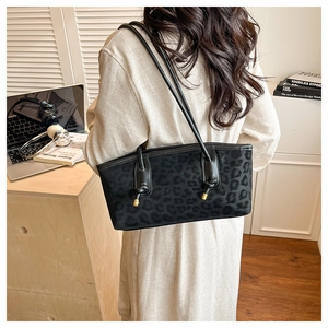 Detail of black leopard print tote bag with suede texture shown in an office setting