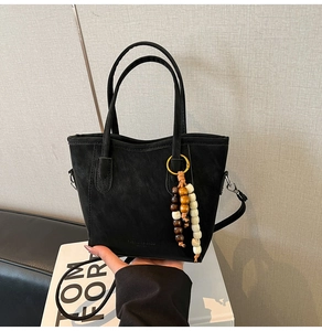 Gros plan du sac seau noir mat avec bandoulière réglable et pendentif en perles ethniques