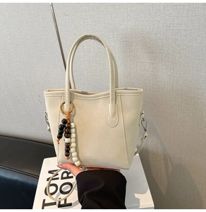 Détail du sac cabas blanc crème avec breloque en perles et bandoulière amovible