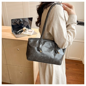 Detail of vintage grey leather tote bag with thin knotted shoulder straps and gold hardware