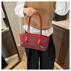 Detail of red leopard print tote bag with knotted handles and gold metal accents
