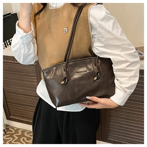 Close-up of retro dark brown tote bag with knurled handle and fashion embossed lettering