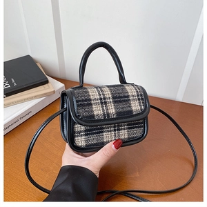 Detail of mini black and white plaid crossbody bag with synthetic leather trim and handle