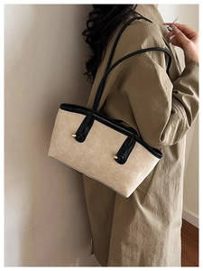 Detailed view of beige suede shoulder bag with black straps and golden metal buckle