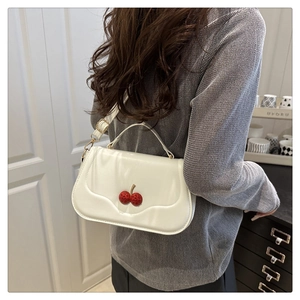 Detailed side view of white leather crossbody bag with 3D cherry accents on model