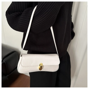 Detail shot of white crocodile pattern baguette bag with a gold buckle worn on shoulder