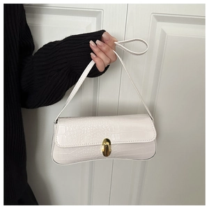 Detail of white crocodile embossed texture on a minimalist handbag with gold metal clasp
