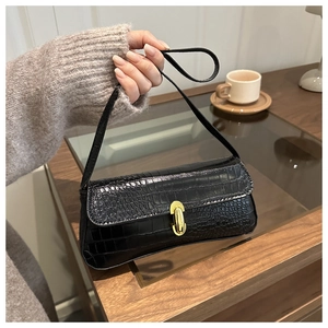 Detail showing the black faux crocodile texture and golden oval metal clasp of the bag
