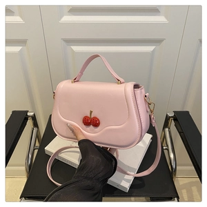 Pink leather square bag with red cherry detail and wave stitching on a book