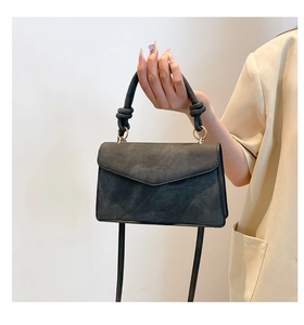 Detail of grey suede handbag with knotted top handle and gold metal ring attachment