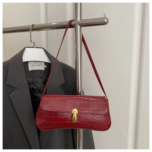 Detail view of deep red crocodile embossed shoulder bag with gold metal buckle