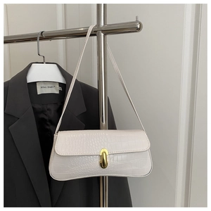 Detail of white crocodile embossed underarm bag with gold rotating lock on hanger
