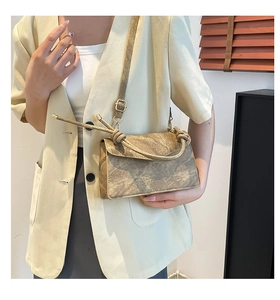 Detail of vintage textured crossbody bag with unique knot handle and gold hardware
