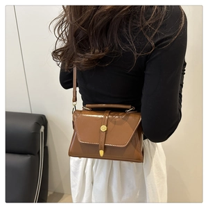 Detailweergave van een bruine vintage crossbodytas met gouden metalen gesp op de rug