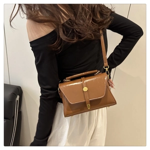 Detailweergave van karamelbruine lederen crossbodytas met metalen sluiting en handvat