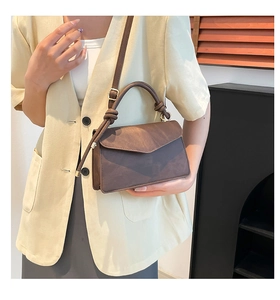 Detail of minimalist dark brown leather crossbody bag with knot handle and flap closure