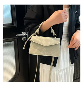 Detail of grey textured crossbody bag with knotted handle and elegant metal hardware