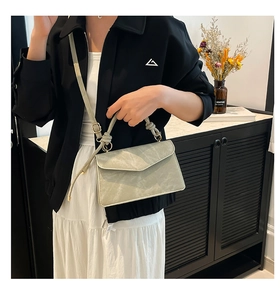 Detail of grey-green crossbody bag featuring a knotted handle and fine leather texture