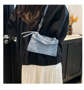 Detail of light blue crossbody bag with knot decor and golden hardware on a person