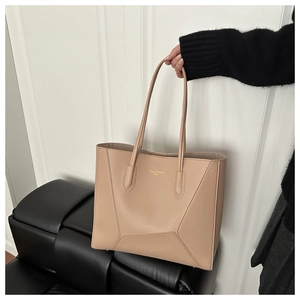 Detail of beige tote bag with geometric stitching and gold logo lettering