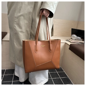 Detail of caramel leather tote bag with asymmetric geometric stitching and logo