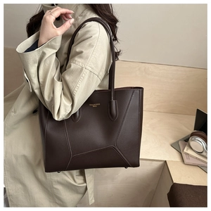 Detail of a large brown leather tote bag with gold lettering for office commuting