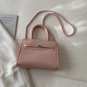 Close-up of pink leather and woven fabric handbag with silver rotating metal lock