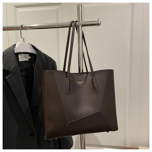 Detail of dark brown leather tote bag with geometric stitching and metal feet
