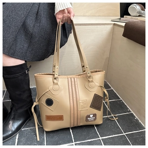Close-up of khaki tote bag featuring fashion heart patches and stitching details