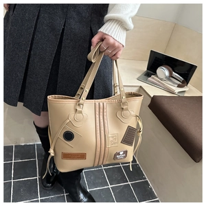 Detail of beige tote bag with patchwork letters and adjustable side drawstrings