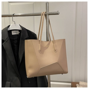 Close-up of geometric stitch tote bag with gold logo on matte apricot leather surface