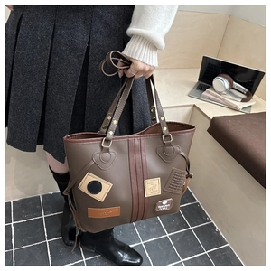 Detailed view of the dark brown tote bag featuring trendy decorative patches and double handles