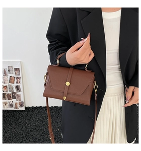Detail view of a dark brown pebble leather crossbody bag with golden metal hardware