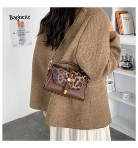 Detail of leopard print flap bag with gold hardware worn by a model in a retro setting