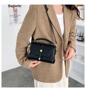 Detail of black pebbled leather crossbody bag with golden hardware on a model