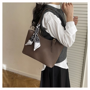 Dettaglio borsa tote marrone in pelle martellata con foulard decorativo in seta sul manico