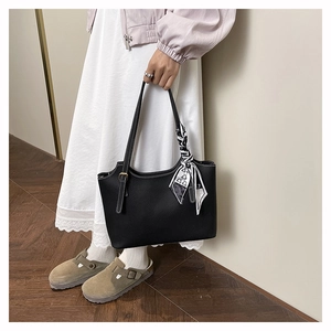 Dettaglio della borsa tote in pelle nera con foulard di seta decorativo sul manico
