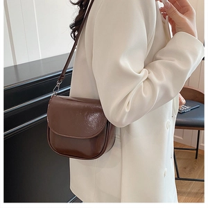 Détail du sac selle marron foncé brillant avec texture de cuir synthétique premium