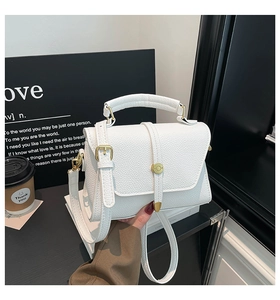 Close-up of white lychee pattern leather handbag with gold metal hardware and top handle